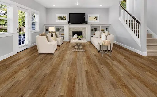 Modern living room with light wood flooring, beige seating, and a fireplace.