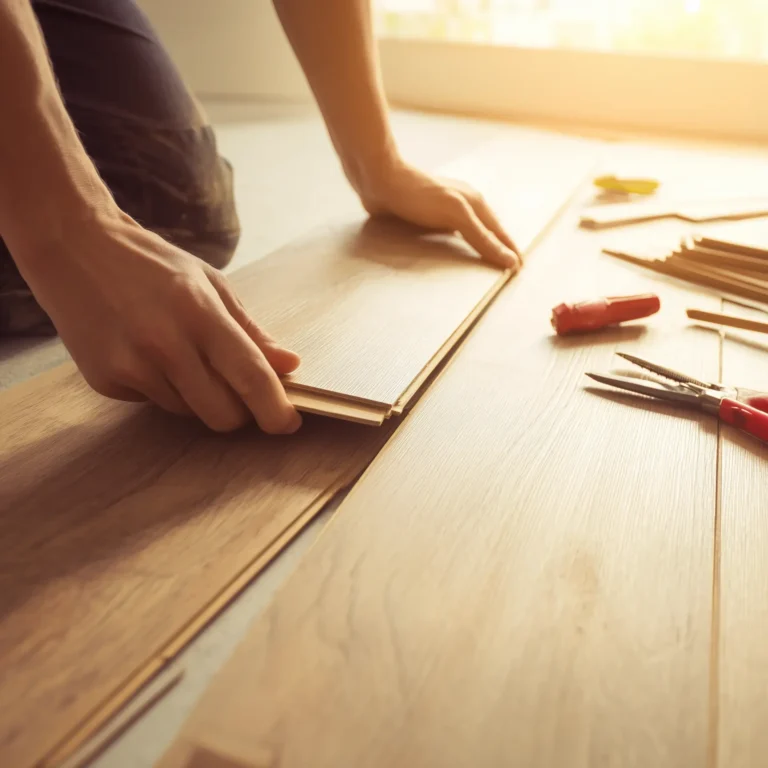 Hands locking wood laminate flooring planks into place.
